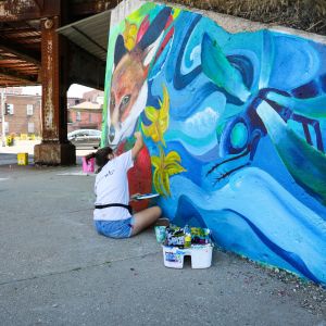 Metro Arts student apprentice painting a mural in downtown Davenport