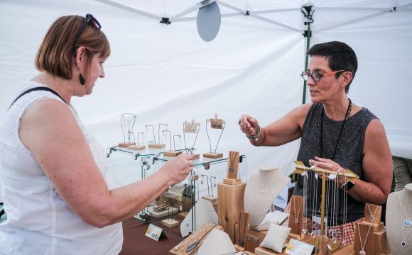 a jewelry vendor showing off her product in a tent in downtown davenport