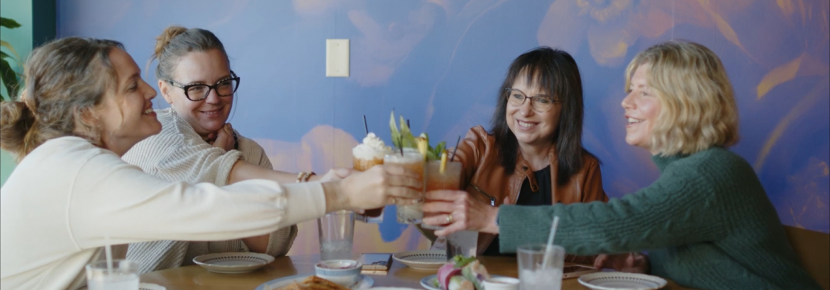 dark wood table with a group of people cheers-ing